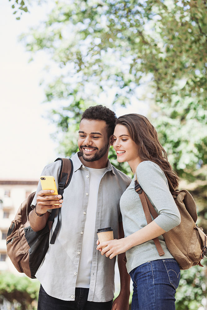 Beautiful happy couple using smartphone. Young joyful smiling wo